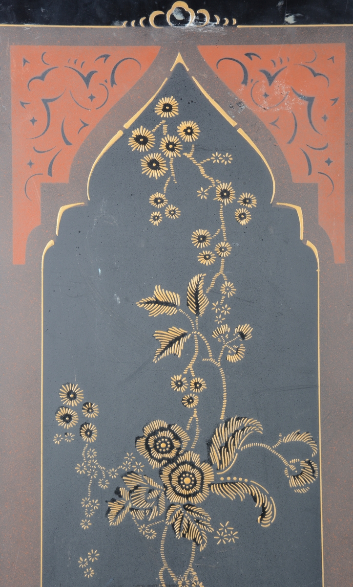 Svart skjermbrett av metall bestående av to paneler. Disse er dekorert med påmalt dekor i form av blomster i en ramme med løkformet overkant og med arabesker.