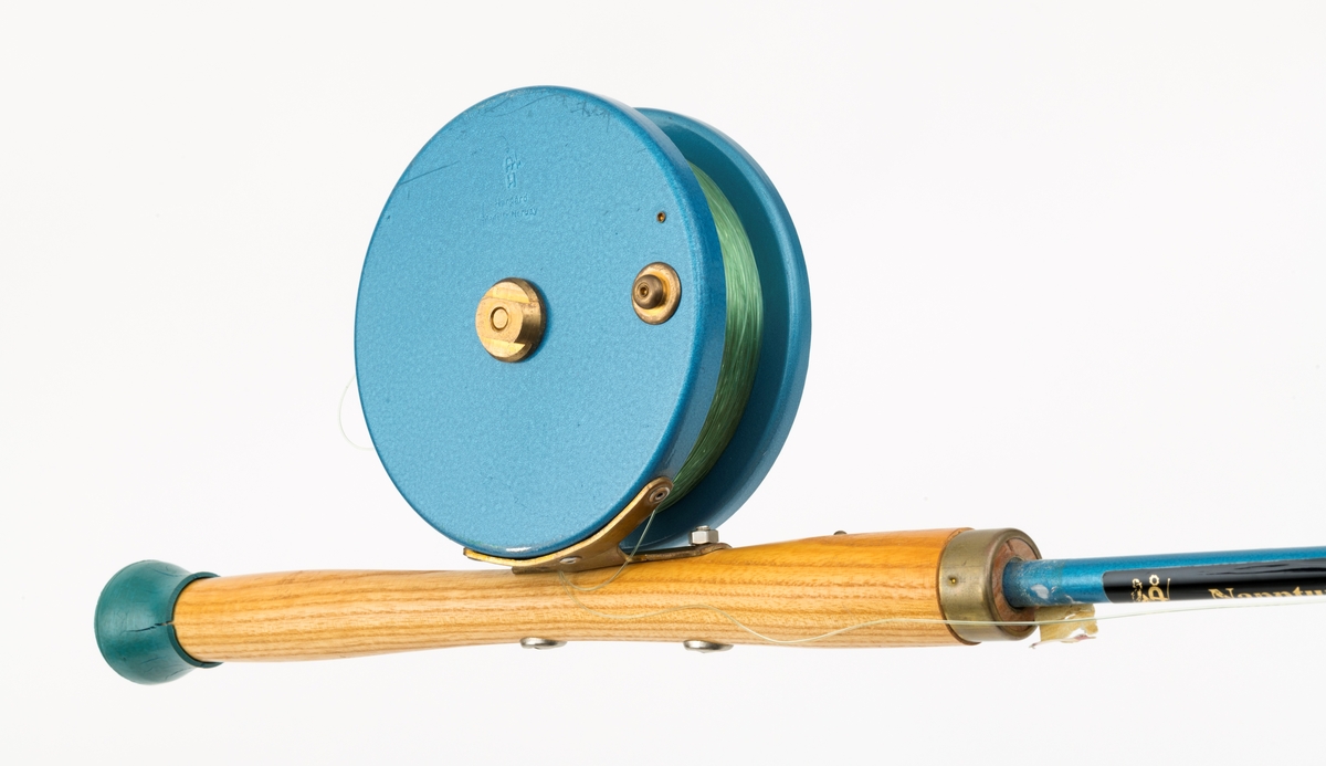 Fiskestang, havfiskestang, pilestang for sjøfiske fra båt produsert av firmaet Asbjørn Hørgård A/S med modellbetegnelsen "Napptun Pilkesett". Det er påmontert pilke- og dorgesnelle på stanga.  Stanga er produsert i massiv glassfiber, håndtak i tre med gummiknott i enden. Snella er skruddd fast til håndtaket med gjennomgående skruer. Snellefoten, antatt av messing, er naglet fast til snella.   
I salgskatalogen"Råd og redskap fra Hørgård" i 1975 er  "Napptun Pilkesett" beskrevet slik: "Asbjørn Hørgård har med sin kveite på 58 kg bevist at man kan ta storfisk med Napptun. Solid 4 1/2' pilkestang, en 5 1/2'' pilke- og dorgesnelle med 100 m 0.70 Triple Fish snøre, 1 Stingsild og 1 May Fly opphenger. Leveres ferdig montert. Pris: kr. 220,-" [Stingsild og May Fly opphenger er ikke montert på stang SJF.15050.]

I salgskatalogen "Råd og redskap fra Hørgård" i 1984 er Snella beskrevet slik: "Napptun snelle 5 1/2' * K(EK) Enklere kan en snelle knapt bli. Du kan enten bruke den som pilkesnelle eller du kan dorge med den på sjøen eller etter større innlandsfisk. Snelle har klikk som gir deg et signal når fisken går på. Klikken slår du på ved å skyve på knotten bak. Den store trommelen gjør at det er lett å ta inn fisk. På kanten av spolen har du en bremseflate, som du legger håndflaten på når fiske renner ut. Kan anbefales sammen Frøya. Pris: Napptun m/klikk kr. 205. 


[Se fanen Opplysninger for informasjon om Asbjørn Hørgård og hans firma.]