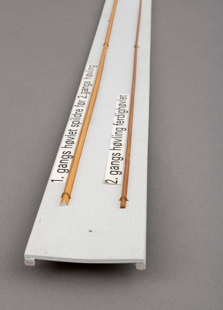 To splitcaneribber, spildrer av bambus (tonkinbambus), montert på en hvitmalt treplate. Spildrene har sitt utgansgpunkt i et bambusråemne (tonkinbambus) som er splittet opp og industrielt behandlet i firmaet Asbjørn Hørgårds maskiner, for deretter å bli limt sammen til fiskestenger.  Montasjen med de to spildrene har vært utstilt i museets basisutstilling om ferskvannsfiske fram til cirka 2013.

På den hvite treplata ses øverst en 1. gangs høvlet spildre før 2. gangs høvling og nederst en spildre (ribbe) etter 2. gangs høvling og som regnes som ferdig høvlet. En stangdel i ferdige fiskestanga, splitcanestanga, bestod av 6 ribber (spildrer). 

[Se referanser og referanser til filer for mer informasjon om hvordan framstillingen av splitkeinstenger foregikk. Se fanen "Opplysninger" for informasjon om Asbjørn Hørgård og hans firma. ]