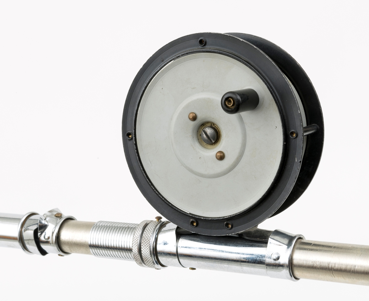 Tre fiskesneller, to fluesneller og en dorge- pilkesnelle, montert på et rør (en stang) med fem snellfester. I og med at det er fem snellefester kan det tyde på at det en gang har vært montert fem sneller på stanga. Snellene er produsert av firmaet Asbjørn Hørgård A/S i Trondheim. I hver ende av røret er det montert fester som gjør det mulig å montere stanga med fiskesneller til vegg. Snellene sitter festet på undersiden av stanga når de brukes, altså med snellefoten opp. 

I salgskatalogen "Råd og redskap fra Hørgård" i 1984 er den blå dorge- pilksnella  beskrevet slik: "Napptun snelle 51/2' * K(EK) Enklere kan en snelle knapt bli. Du kan enten bruke den som pilkesnelle eller du kan dorge med den på sjøen eller etter større innlandsfisk. Snelle har klikk som gir deg et signal når fisken går på. Klikken slår du på ved å skyve på knotten bak. Den store trommelen gjør at det er lett å ta inn fisk. På kanten av spolen har du en bremseflate, som du legger håndflaten på når fiske renner ut. Kan anbefales sammen Frøya. Pris: Napptun m/klikk kr. 205."
Diameter sidedeksel: 14 cm. Bredde målt frfa ytterside av sveivknapper til ytterside av sidedeksel: 8, 2 cm. 

Fluesnellene: Snellene består av spole (trommel), sidedeksler, ramme, sveiv og snellefot. Sveiva er montert direkte på spolen. 
På svart og hvit fluesnelle som er merket Trout Fly sitter sveivknappen løst. Snella merket Trout Fly har disse målene: 
Bredde målt fra ytterside av sveivknapp til ytterside av sidedeksel: 5,6 cm. Bredde spole, innvendig målt: 2,4 cm Diameter sidededeksel: 9,1 cm.
I Hørgård-firmaets bok "Norwegian made fishing tackle" fra 1964 er denne snelletypen beskrevet slik: "Trout Fly 3 1/2" Guttsnelle, passende for flue-, mark- og dorgefiske."

På svart og hvit fluesenlle som er merket Å H Hørgård er disse målene tatt: 
Bredde målt fra ytterside av sveivknapp til ytterside av sidedeksel: 6,4 cm. Bredde spole, innvendig målt: 2,2 cm Diameter sidededeksel: 8,9 cm.
I Hørgård-firmaets bok "Norwegian made fishing tackle" fra 1964 er denne snelletypen beskrevet slik: "Ørret fluesnelle 3 1/2'' ca. 170 gr. Presjonsarbeid med utsøkt materiale. Helstøpt lettmetall. Brennlakkert. Kapasitet: 30 yds. tapered fluesnøre og ca. 50 yds. bakline."



[Se fanen Opplysninger for informasjon om Asbjørn Hørgård og hans firma.]