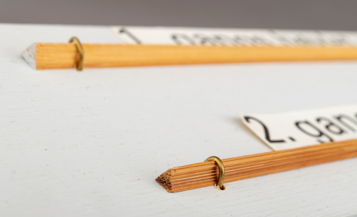 To splitcaneribber, spildrer av bambus (tonkinbambus), montert på en hvitmalt treplate. Spildrene har sitt utgansgpunkt i et bambusråemne (tonkinbambus) som er splittet opp og industrielt behandlet i firmaet Asbjørn Hørgårds maskiner, for deretter å bli limt sammen til fiskestenger.  Montasjen med de to spildrene har vært utstilt i museets basisutstilling om ferskvannsfiske fram til cirka 2013.

På den hvite treplata ses øverst en 1. gangs høvlet spildre før 2. gangs høvling og nederst en spildre (ribbe) etter 2. gangs høvling og som regnes som ferdig høvlet. En stangdel i ferdige fiskestanga, splitcanestanga, bestod av 6 ribber (spildrer). 

[Se referanser og referanser til filer for mer informasjon om hvordan framstillingen av splitkeinstenger foregikk. Se fanen "Opplysninger" for informasjon om Asbjørn Hørgård og hans firma. ]