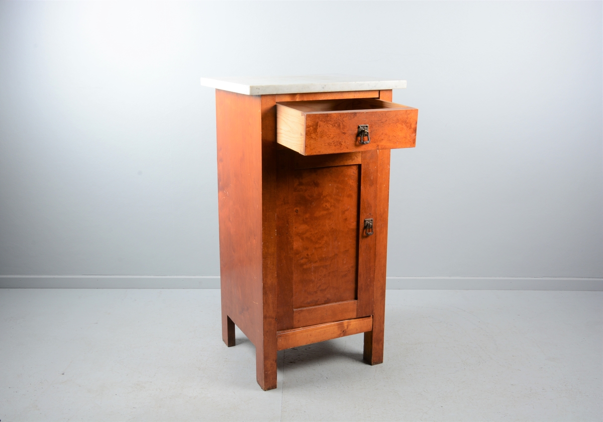 Nattbord med skuff, skap og marmorplate på toppen (plata er laus). Skuffen og skapet har messingknotter. Skapet har fyllingsdør som har opning mot venstre og skal dermed stå på venstre side av senga.