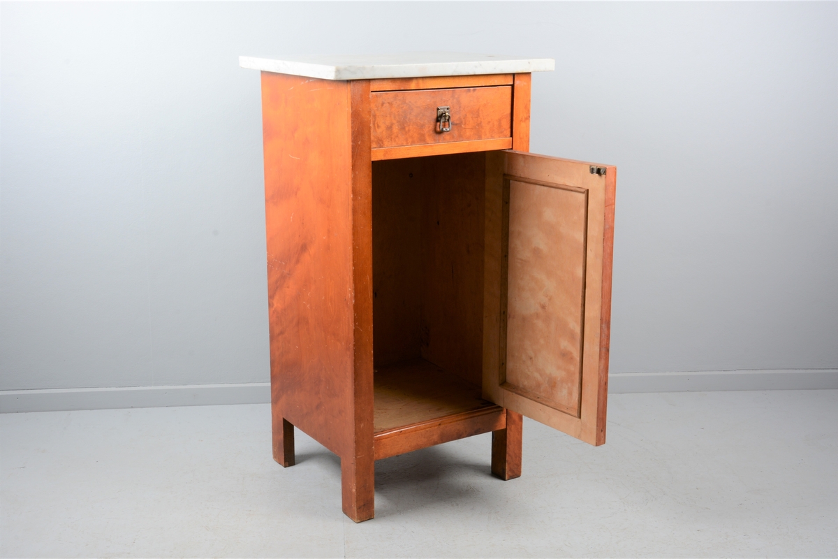 Nattbord med skuff, skap og marmorplate på toppen (plata er laus). Skuffen og skapet har messingknotter. Skapet har fyllingsdør som har opning mot venstre og skal dermed stå på venstre side av senga.
