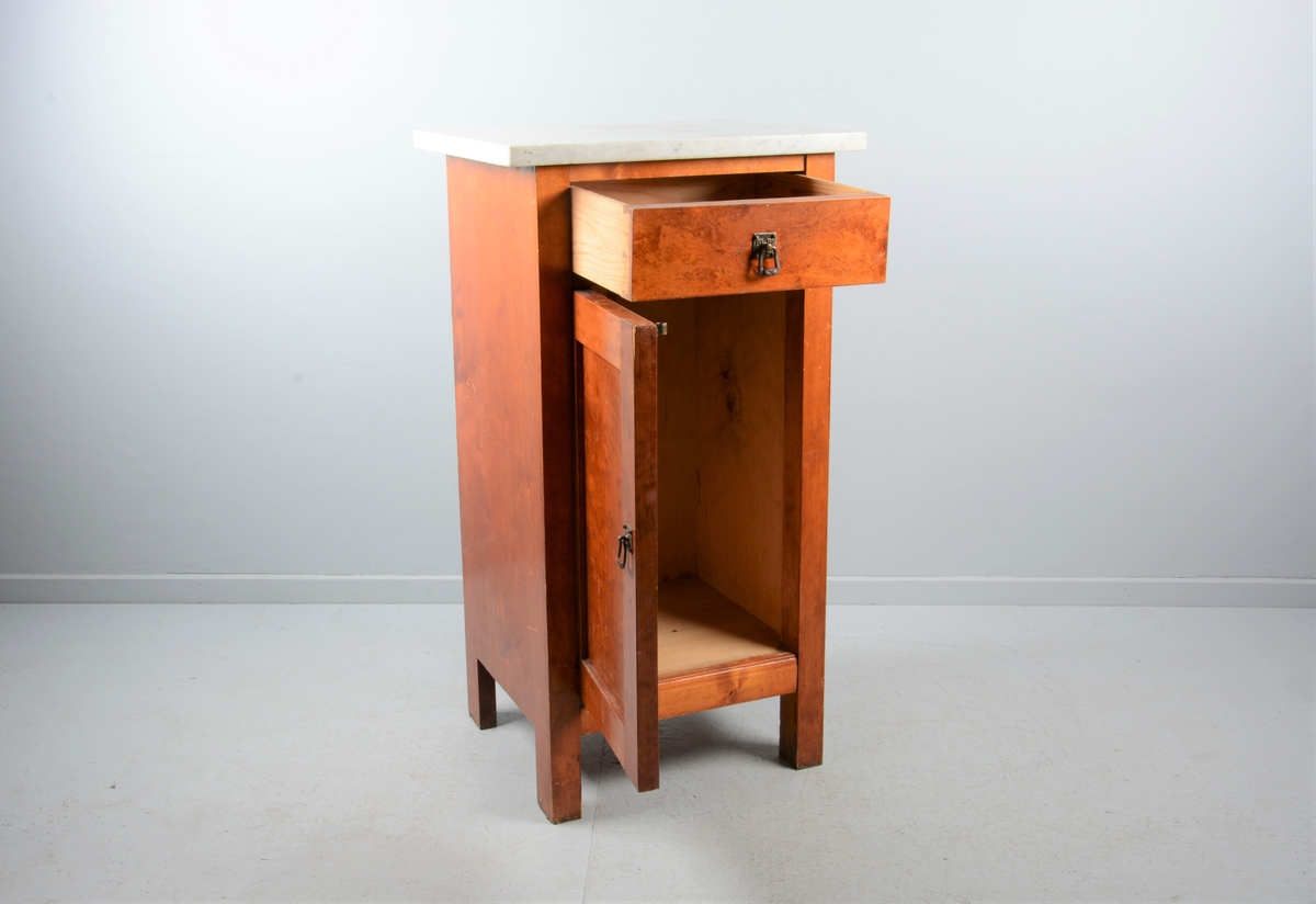 Nattbord med skuff, skap og marmorplate på toppen (plata er laus). Skuffen og skapet har messingknotter. Skapet har fyllingsdør som har opning mot venstre og skal dermed stå på venstre side av senga.