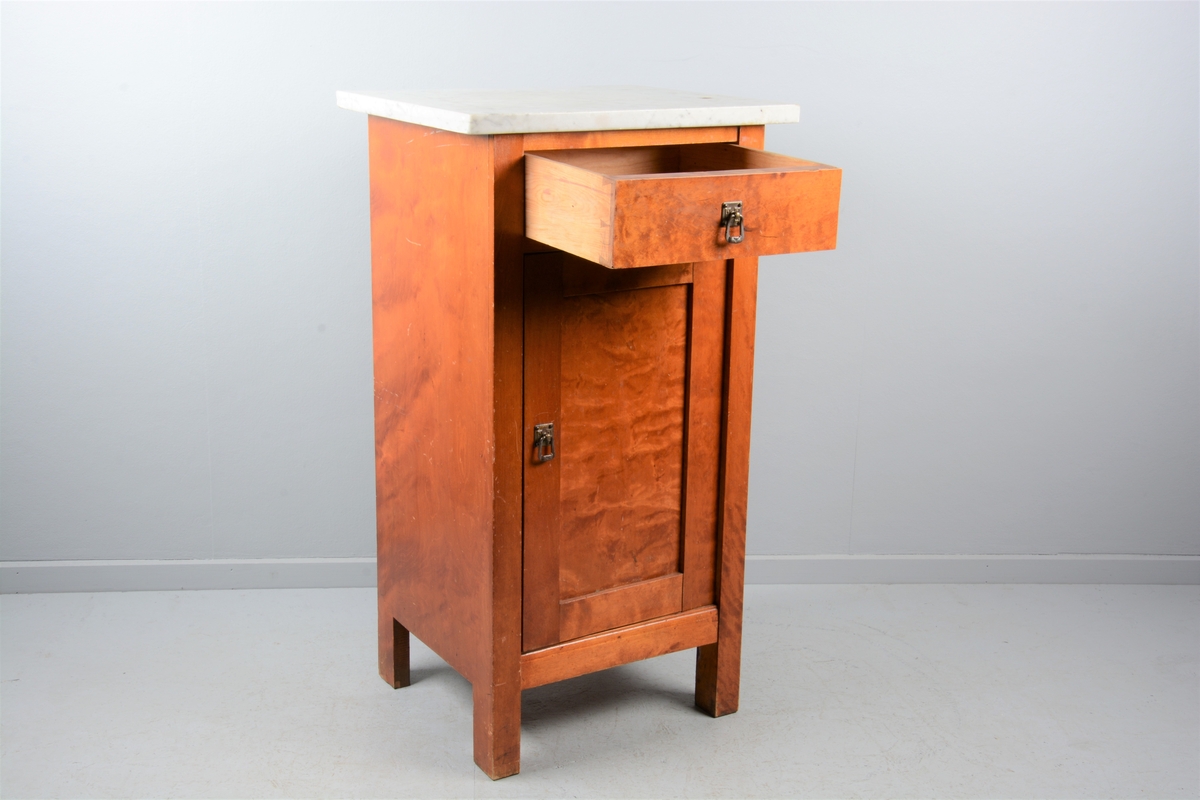 Nattbord med skuff, skap og marmorplate på toppen (plata er laus). Skuffen og skapet har messingknotter. Skapet har fyllingsdør som har opning mot venstre og skal dermed stå på venstre side av senga.
