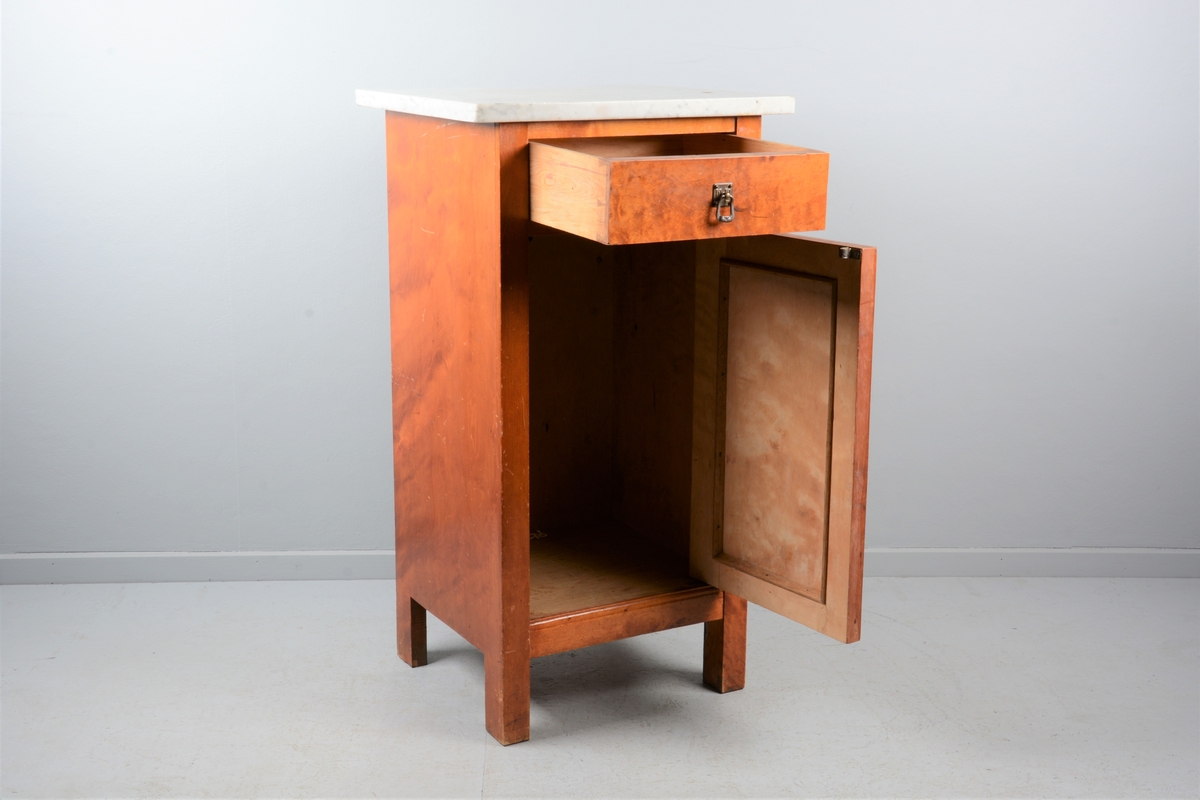 Nattbord med skuff, skap og marmorplate på toppen (plata er laus). Skuffen og skapet har messingknotter. Skapet har fyllingsdør som har opning mot venstre og skal dermed stå på venstre side av senga.
