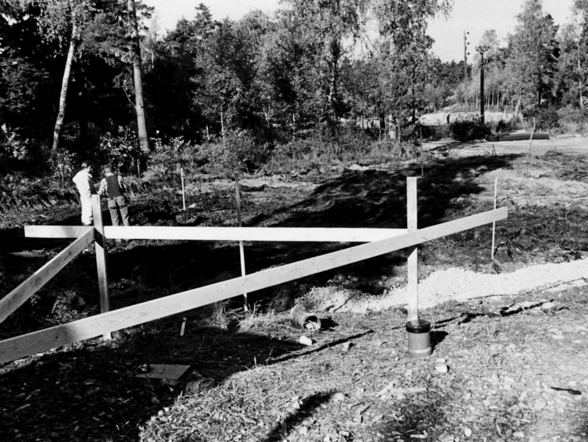 Nybyggnation av tre förråd 1986.

Några blandade bilder från de samtida byggprojekten i Utö läger; livsmedelsförrådet, kokhuset och Värnskolans förråd. 

Bild 1: Staffan Löding och Kurt Madell diagonalmäter plattan så att stomresningen kan få starta.

Bild 2: Stålstommen till plåtförrådet rest.

Bild 3: Profiler till en av de andra byggnaderna monteras.

Bild 4: Kurt Madell och Kjell Strömkvist studerar ritningar.

Bild 5: Sulan till livsmedelsförrådet rak och fin!