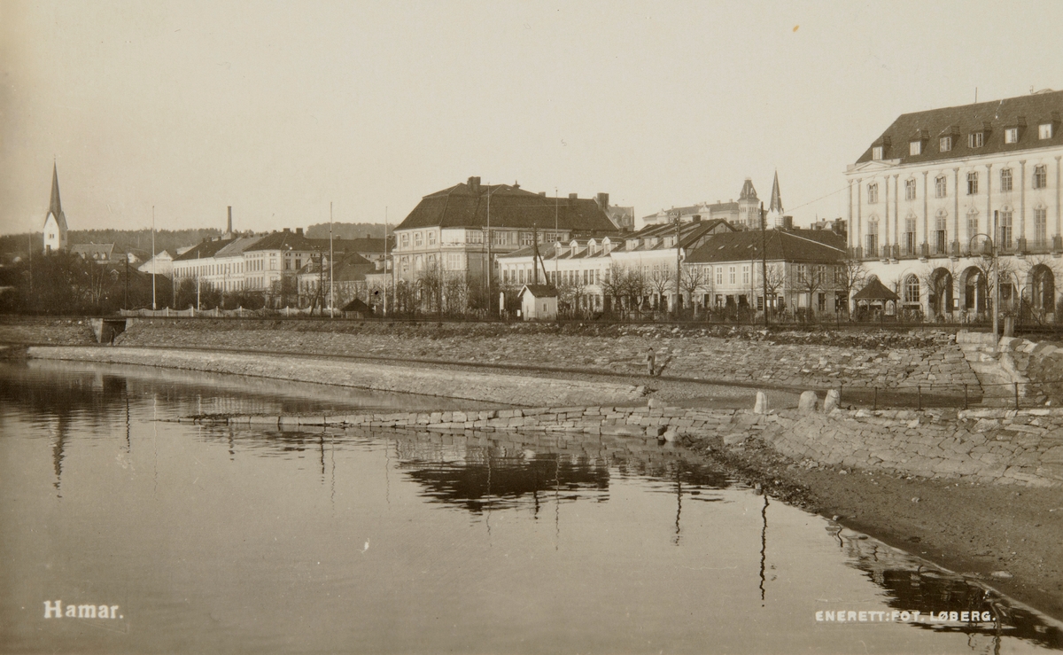 Postkort, Hamar by sett fra Hamarbukta, Hamar Sparebank sto bak byggingen av Festiviteten, byggestart i 1918, banken, Hamar samlag og Festivitetskinoen kunne flytte inn i 1920, teatersalen ble ikke ferdig før i 1927, jernbanefylling, liten steinbrygge utenfor Victoriaundergangen med veg opp til Jenbanebrygga, steinmuring, Strandgatehager med lysthus, 
åttemeterplanet,