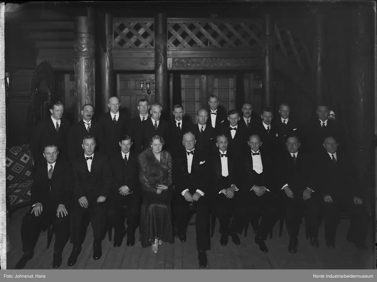 Gruppebilde fra Hydros 25 års jubileum. General direktør Axel Aubert sittende i midten foran. Kvinne sittende ved siden av, resten av gruppen er dresskledde menn.