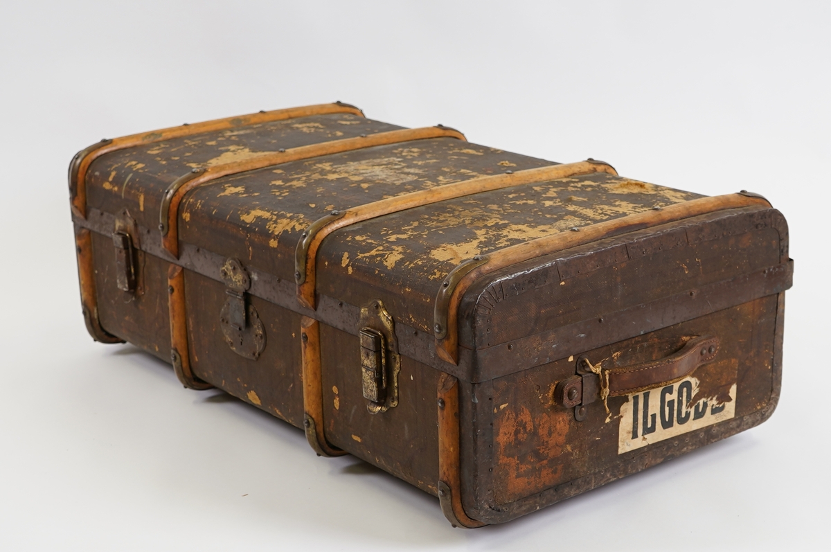 Koffert av tre kledd med strie på utsida og papir på innsida. På utsida er det beslag av tre forsterka med metall. Innvendig er kofferten delt med ei skuff til å løfte opp.