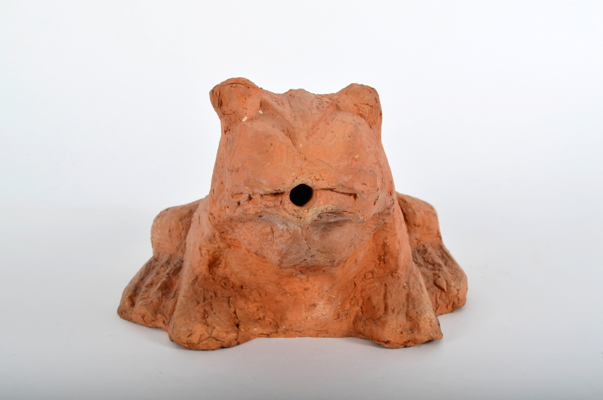 Froskefigur i rød terracotta.