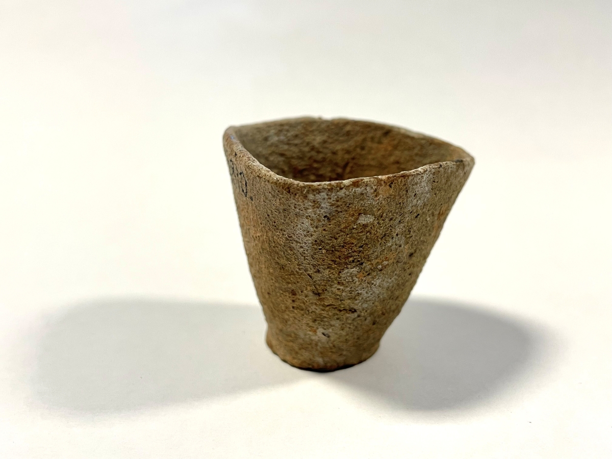 Trekantigt formad degel i tunt, ljusbeigt, sandmagrat lergods. Cirkulär botten. Benämns "Hessisk degel" i Smålands museums huvudkatalog. Möjligen för smältning av metaller.