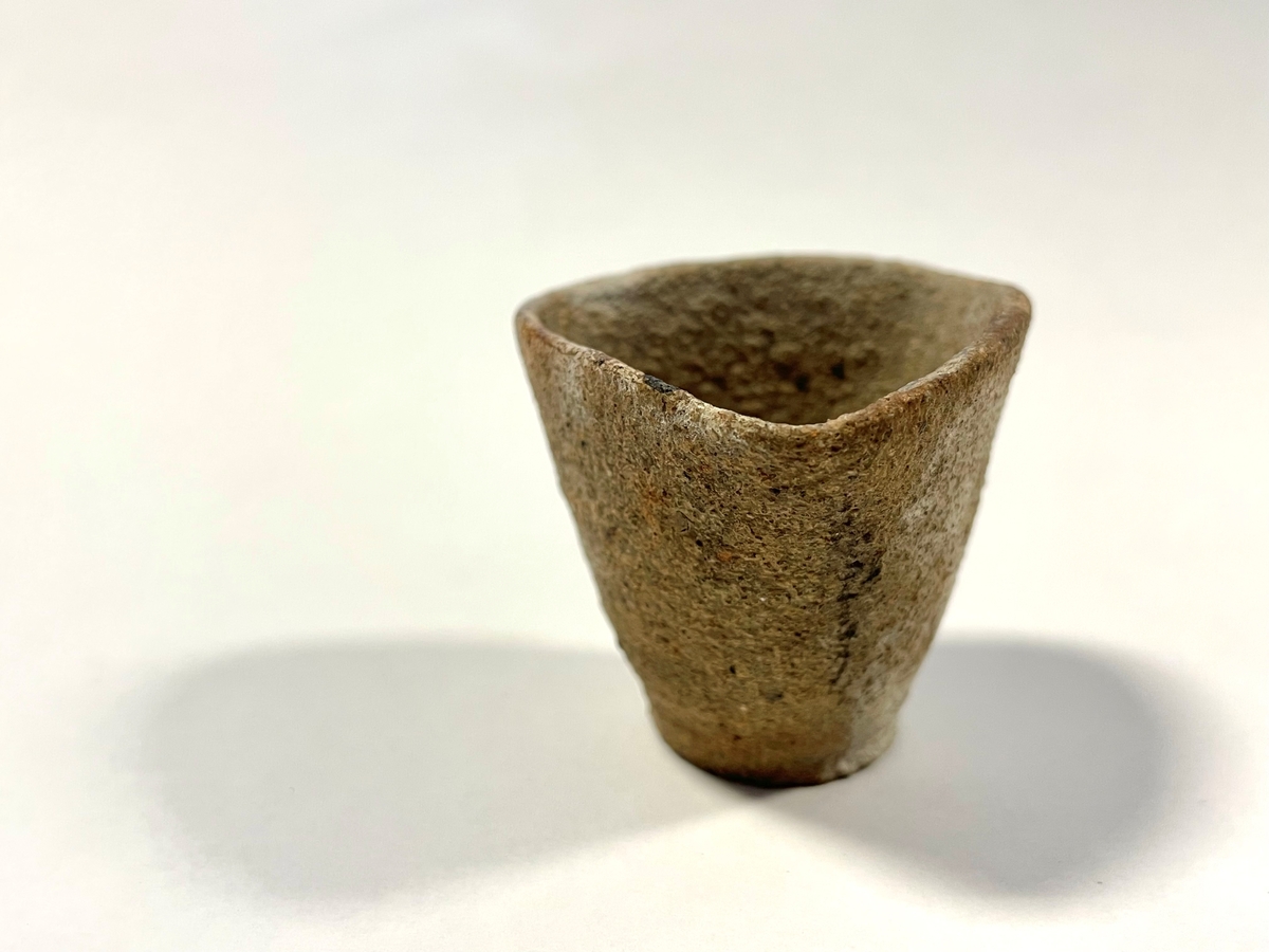 Trekantigt formad degel i tunt, ljusbeigt, sandmagrat lergods. Cirkulär botten. Benämns "Hessisk degel" i Smålands museums huvudkatalog. Möjligen för smältning av metaller.