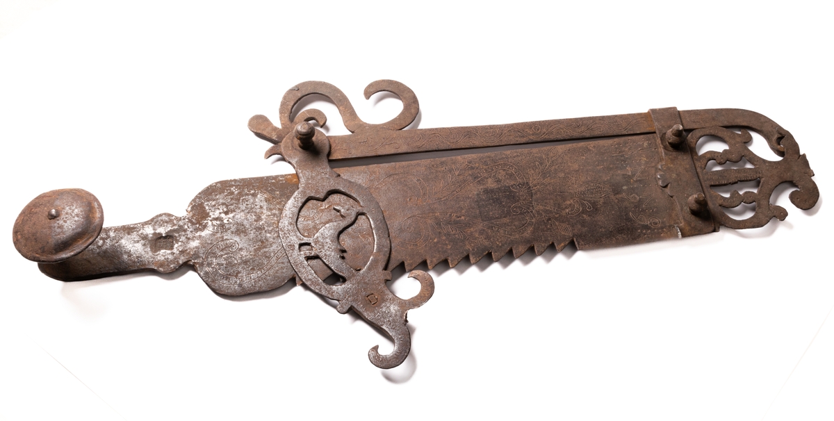 Järnföremål, okänd användning. Möjligen slangringsregel till stor ugn. Märkt 1799.
Avlångt med brutna ornament vid ändanrna liknande krona och fågelfigur.
Till vänster ett kraftigt knoppformigt handtag. Framsidan täckt av ristade ornament: slingor med glesa tvärstreck, blommor, m.m.
Otydligt smedsmärke, se skiss.