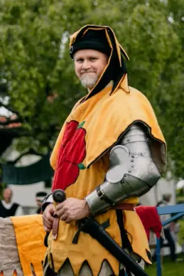 Mann i platerustning med gul kjortel over. Kjortelen har en rød rose på brystet