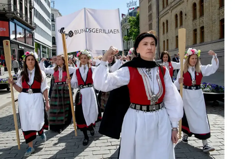Et tog i regi Bunadsgeriljaen. Damer i bunad bærer årer og holder knyttneven opp. Tidligere leder Anja C. Solvik går i front.