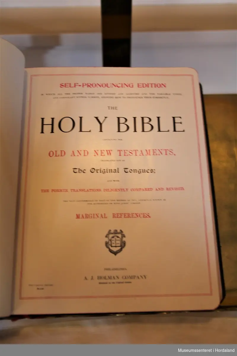 Stor, svart bibel med tittelen "Holy Bible" i gylne, dekorative bokstaver på forside og rygg.