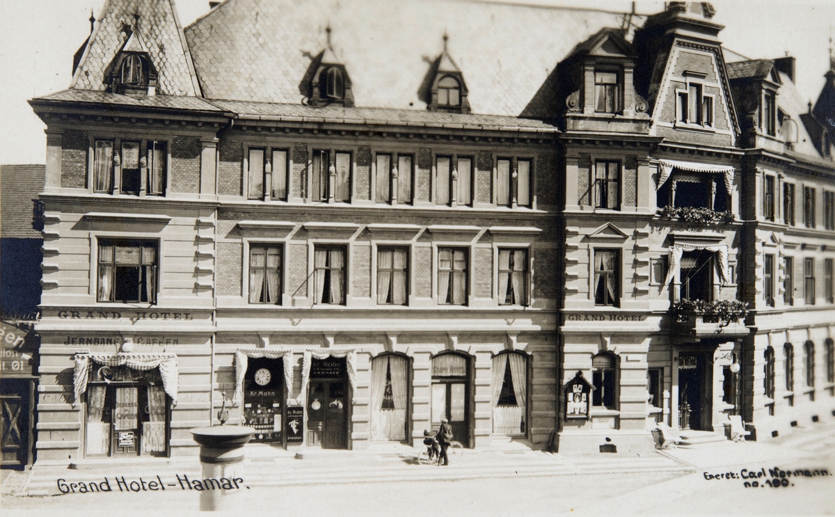 Postkort, Hamar, Jernbaneplassen, Grand Hotell, Jernbane-Cafeen, urmaker Kr. Mohn hadde butikk her fra 1912 til 1925, Mohn kjøpte urmakerforretningen av A. M. Sveen som hadde stratet virksomhet her i 1895,