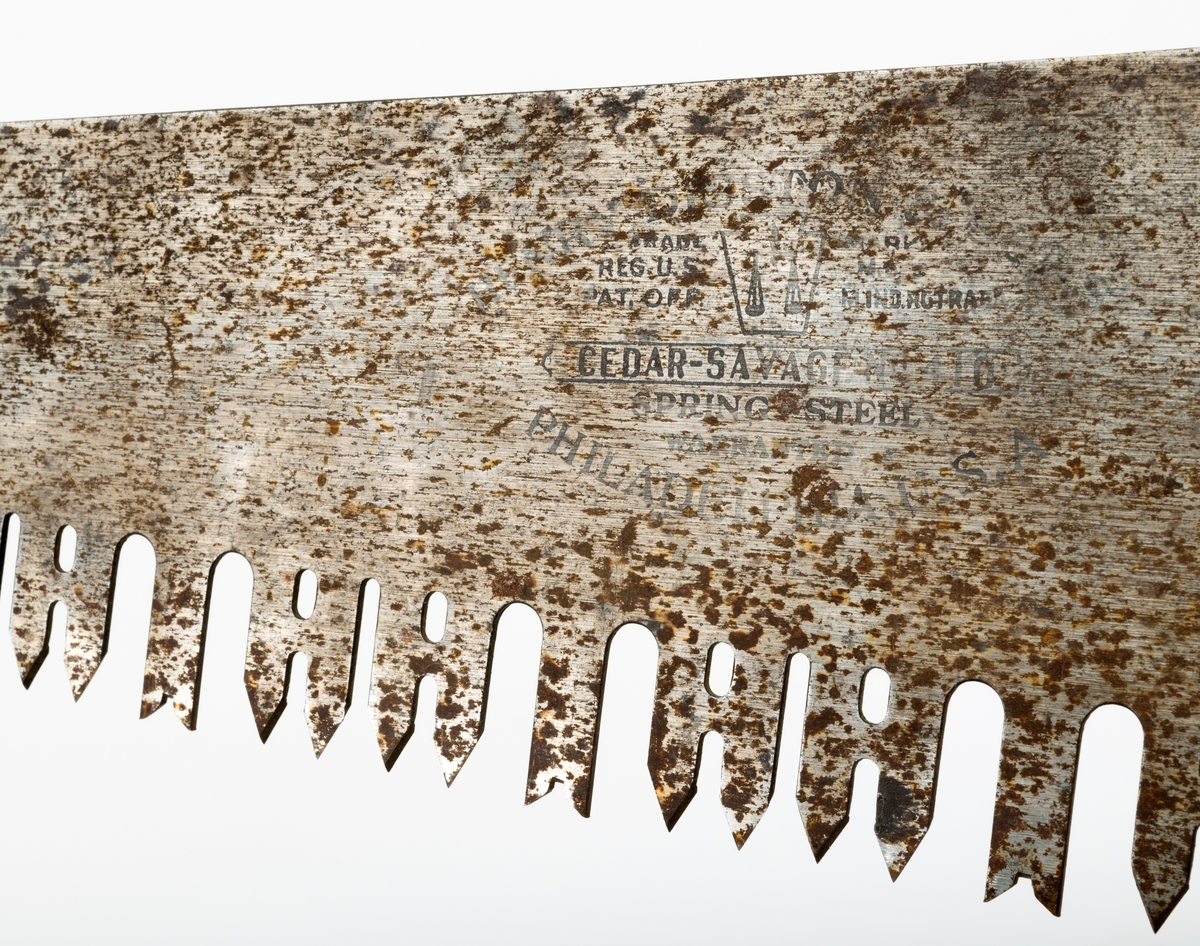 Svans - enmannssag brukt til felling og kapping av tømmer. Redskapet er 118,5 centimeter langt. Herav utgjør bladet eller klingen 106,6 centimeter, målt langs bladryggen. Bladet tiltar i bredde fra den fremre mot den bakre enden, fra 6,7 til 17,6 centimeter. Bladstålet er noe tjukkere på «tannsida» enn på ryggsida, henholdsvis 1,8 og 1,4 millimeter. Denne saga har høveltenner med V-formete innsnitt i ytterendene. Mellom hver høveltann er det to par liketannete rivtenner, som er fasfilte, vekselvis mot den ene og den andre sida. Her må intensjonen ha vært at høveltennene skulle gjøre dybdesnitt mens rivtennene, som er viggete, skulle utvidet skåret og dermed forebygge at friksjonen ble for stor. De U-formete sponrommene på begge sider av høveltennene er om lag 3,8 centimeter djupe og 1,1 centimeter brede sponrom. Sponrommene mellom rivtennene er noe smalere og grunnere. Egglinja er en aning konvekst buet. Den fremre delen av bladryggen er noe konkavt buet i drøyt 80 centimters lengde, mens den bakre enden er noe mer rettlinjet. Saha har et handtak, lagd av et 2,3 centimeter tjukt bord. Handtaket har et ovalt gripehull med avrundete kanter. I den fremre enden er det ei spalte som bladets bakre endestykke er stukket inn i. Deretter er forbindelsen mellom handtaket og bladet låst ved hjelp av tre messingskruer. Handtaket har også avtrykk etter en ståltein som har vært påskrudd den ene handtakssida, vinkelrett på redskapets lengderetning. Dette er antakelig spor etter feste for en såkalt «sagkamerat», ei spiralfjær med en krok som ble slått inn i treets yteved med sikte på at fjæra skulle lette skogsarbeiderens skyvebevegelser. Bakerst på bladet, oppunder bladryggen, er det et gjennombrutt hull. Det finnes også et tilsvarende hull i den fremre enden. Her kan det ha vært mulig å feste et ekstra handtak, for dermed å kunne bruke saga som tomanns stokksag.

Sagbladet er stemplet «HENRY DISTON & SON  TRADE MARK  REG. U.S, PAT. OFF. CEDAR SAVAGE No 410 SPRING STEEL  WARRANTED  PHILADELPHIA U.S.A.»., Det midtre skruehodet på handtaket er også merket med denne produsentens navn - «DISTON PHILA».