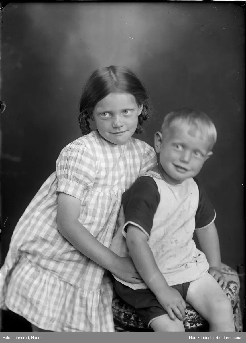 Portrett. To barn sittende i studio.