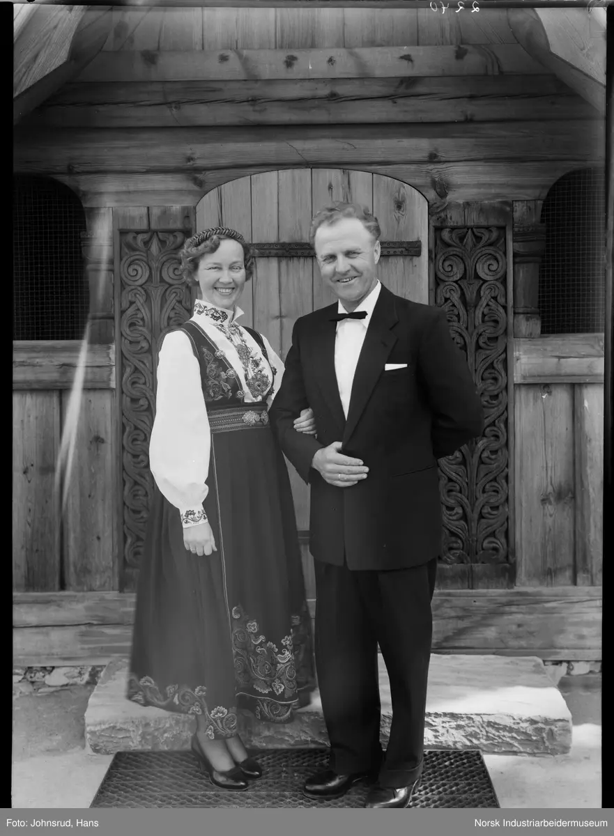 Brud i bunad og brudgom stående foran Heddal Stavkirke.