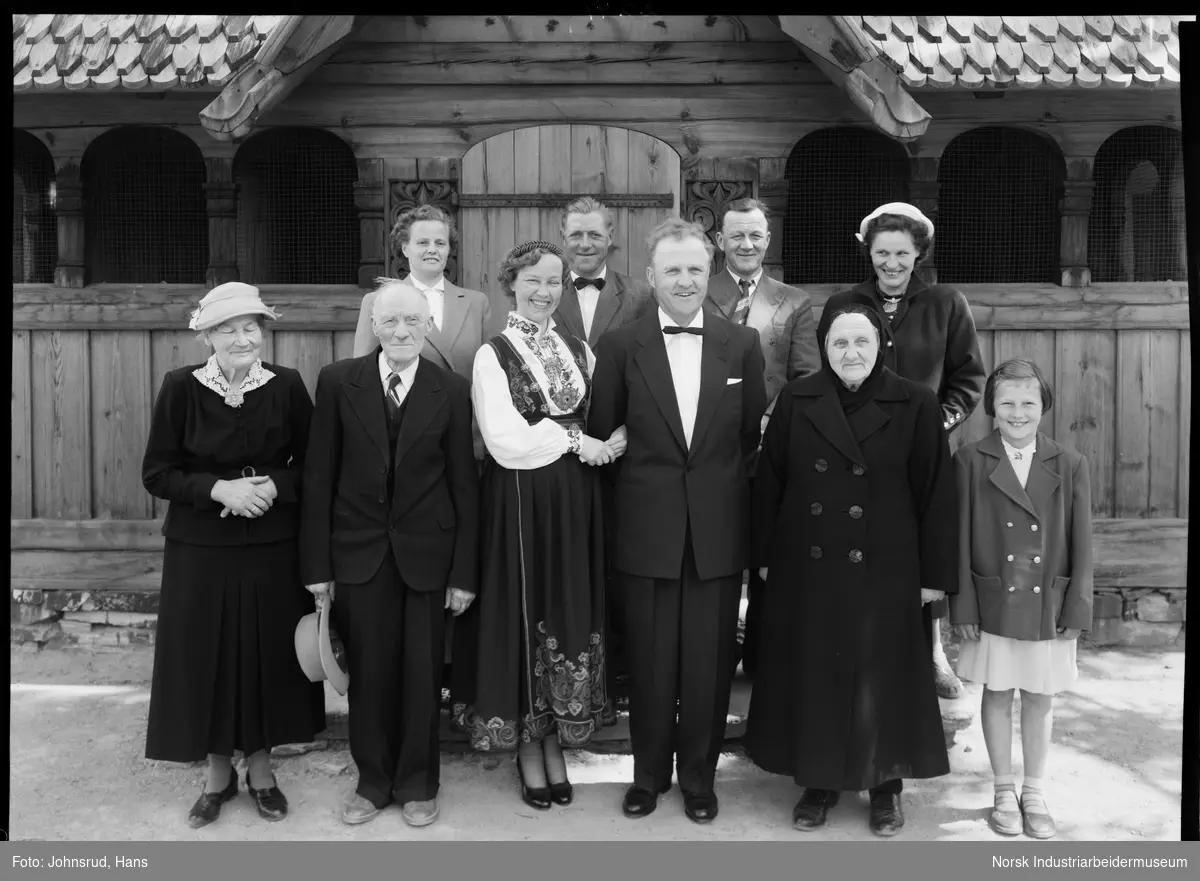 Gruppeportrett. Brudefølge oppstilt foran Heddal Stavkirke. 