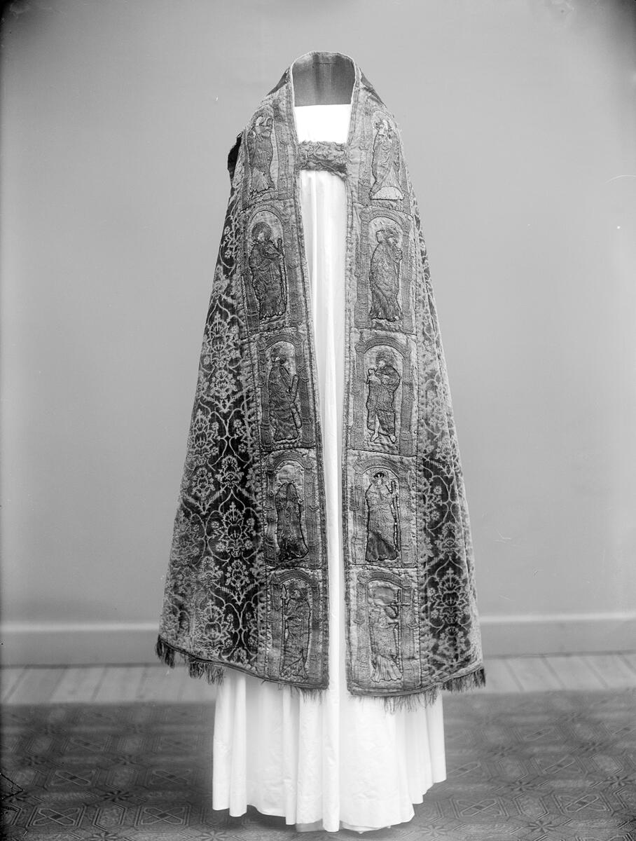 Korkåpa av skuren brungul sammet (ursprungligen röd) med granatäpplemönster och broderier. Kåpan är daterad till Sturegotiken och är troligen ett Vadstena-arbete.

Längs kåpans ytterkant ett band i rött, blått och guld, kantat av silkesfrans randad i flera partier i ursprungligen rött och grönt - nu gulgrått. Utmed framkanterna linnebårder med figurer i aediculor, guld, silver och mångfärgat silke. Å högra sidan jungfru Maria, Petrus, Johannes Döparen, helgon med stav och helgon med kors. Å vänstra sidan okända helgon, Sankt Paulus, Sankt Andreas och okänd apostel med spjut. Figurerna inom rundbågar av guld, på marken strödda blommor.

Vid nacken på rött ylle (ursprungligen täckt av rött taftliknande siden) syns Kristus som smärtoman i halvfigur omgiven av två Guds lamm, på dipens Marie bebådelse med inskrift "AVE MARIA GRA". På broderierna strödda metallpajletter.

Tyget är troligen vävt i Italien under 1400-talets andra hälft. Kåpans montering med band och silverfrans är ursprunglig och kan dateras till 1400-talets senare del eller omkring 1500. Broderierna är troligen utförda i Tyskland under 1400-talets andra hälft. Brämets broderi delvis ibroderat, troligen under 1600- eller 1700-talen.