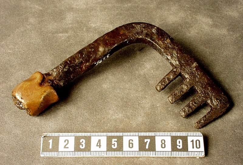 Fyr-kloigt ax vinkelrätt avsatt mot skaftet  detta är en bit upp omlindat med ett 23 mm brett bronsband ovanför det är skaftet avbrutet enligt orginalkatalogen funnet vid odling av äng 1884 i hummelbos
av järn, och med brons, 4 3/8 tum hög, funnen 1884 vid odling i äng, vid hummelbos.