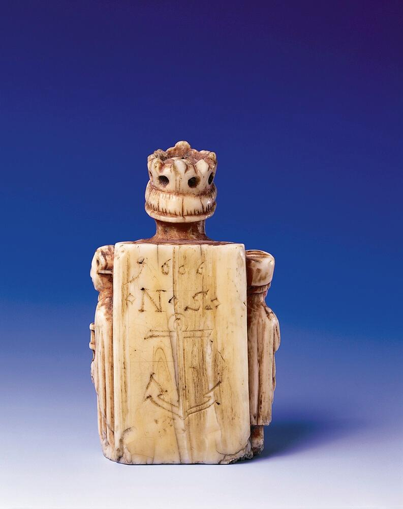 Schackkung av valrosstand med två smärre bilder på sidorna. Krona på huvudet, delvis rödmålad. På baksidan märkt med ett ankare, samt: "1606" och "* N S *". Personen till vänster om kungen är iklädd en lång dräkt och rund mössa, den högra mannen är är barhuvad och bär en knappförsedd dräkt med mantel över. Han håller också en spira eller kort stav i händerna. Pjäsen är genomborrad från kungen hjässa och rakt ner.

Det är osäkert om den röda färgen som man ser spår av är original eller senare ditmålad, men den måste ha påförts före år 1606. Det inristade ankaret kan tyda på att pjäsen vid 1600-talets början ägdes av en sjökapten eller sjöman, men vi saknar kunskap om vem som ursprungligen förde pjäsen till Gotland. Var den en del av ett komplett schackspel eller kom den till ön som ensam souvenir?

Pjäsen bör ha kommit i donatorns (läroverkslektor C J Bergman) ägo mellan åren 1846-1874. 1874 vittnar nämligen Bergmans kollega vid läroverket och blivande museiföreståndaren P A Säve om att den märkliga kungafiguren finns hos Bergman och att han lovat skänka den till det planerade museet. Fram till 1846 hade kungen haft en speciell användning: som handtag i en klocksträng i sessionssalen på Skomakargillets hus i hörnet Ryska gränd och Övre och Nedre Finngränd i Visby. Klocksträngen manövrerade en klocka som var upphängd i taket, varmed åldermannen äskade tystnad vid gillets sammankomster. Gillet höll sina möten i detta hus från år 1592-1846 (då gillet upplöstes), men inskriptionen med årtalet 1606 antyder att det inte kommit i Skomakargillets ägo förrän under 1600-talets första hälft.

Enligt Roosval och af Ugglas är pjäsen sannolikt tillverkad någon gång 1350-1370.