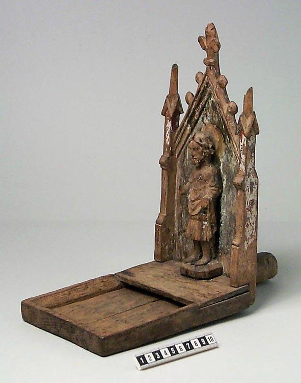 Kollekttavla av ek. Uthuggen bricka delvis täckt med platta. Gavelformat bakstycke med korsblomma, krabbor och fialer. Fialerna är skadade upptill.

En snidad manlig skulptur - möjligen föreställande S:t Olof - står med ryggen mot bakstycket på ett litet podium. Han har vågigt hår och skägg. Armarna saknas och han är fastsatt i podiet med ett rostig spik. På bakstycket en målad gloria och färgrester. Rostig spik på baksidan av bakstycket och ett enkelt handtag. Några runda hål efter skadedjur på handtaget.