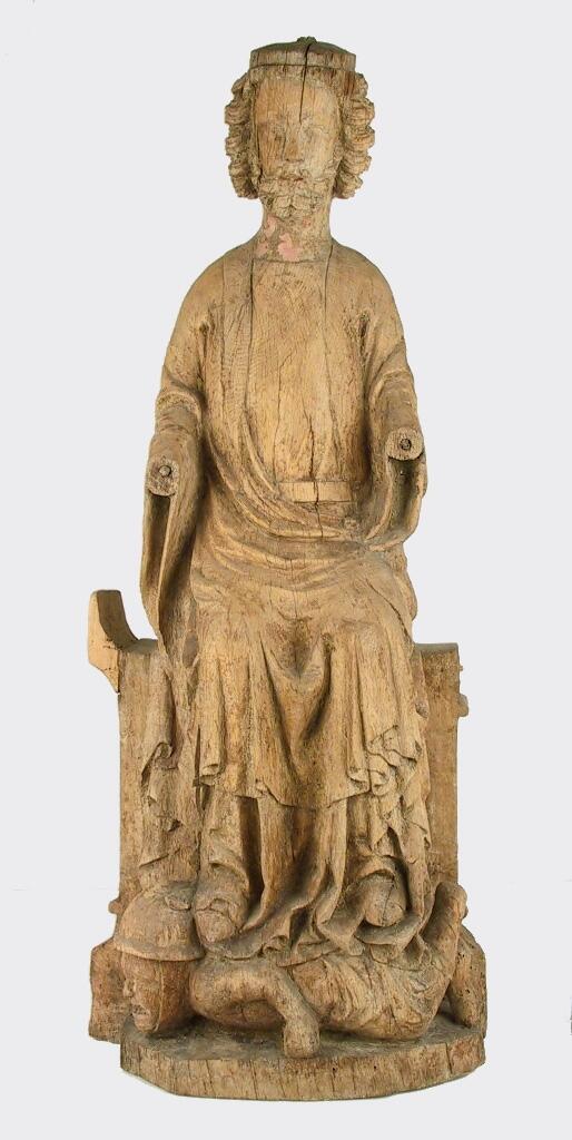 Skulptur av trä som föreställer tronande manligt helgon, troligen S:t Olof.

Han bär lång klädnad med mantel draperad över axlarna, överarmarna och knäna. Båda underarmarna saknas. Han har halvlångt, lockigt hår och skägg och på hjässan har troligen suttit en krona. Med sina skoklädda fötter trampar helgonet på en figur som ligger på mage. Denna figur bär slät hjälm och ansiktet uttrycker skräck. Dess ben och armar är skadade.

I ansiktet finns vissa färgrester kvar. Tronen är skadad och skulpturens baksida är urtagen.

Enligt Johnny Roosval i "Medeltida konst i Gotlands Fornsal" är skulpturen av ek och tillverkad av "Hamramästaren" och "Bungemästaren". Roosval daterar den till höggotik, cirka 1295-1330.

Enligt originalkatalogen är den på mage liggande figuren en romersk krigare - såsom kyrkan förtrampande den världsliga makten.