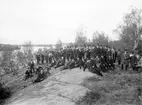 Ordensmedlemmar i samfundet SHT samlade för fotografering. Platsen har lokaliserats till trakten av Rimforsa på gården Linnäs ägor med utblick över sjön Järnlunden.