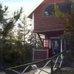 Solen står lågt över Kvädölandet i Gryts skärgård och slår glans mot arkitekt Magnus Tryséns sommarhus. Han har själv förstärkt stunden genom denna handkolorering från omkring förra sekelskiftet.