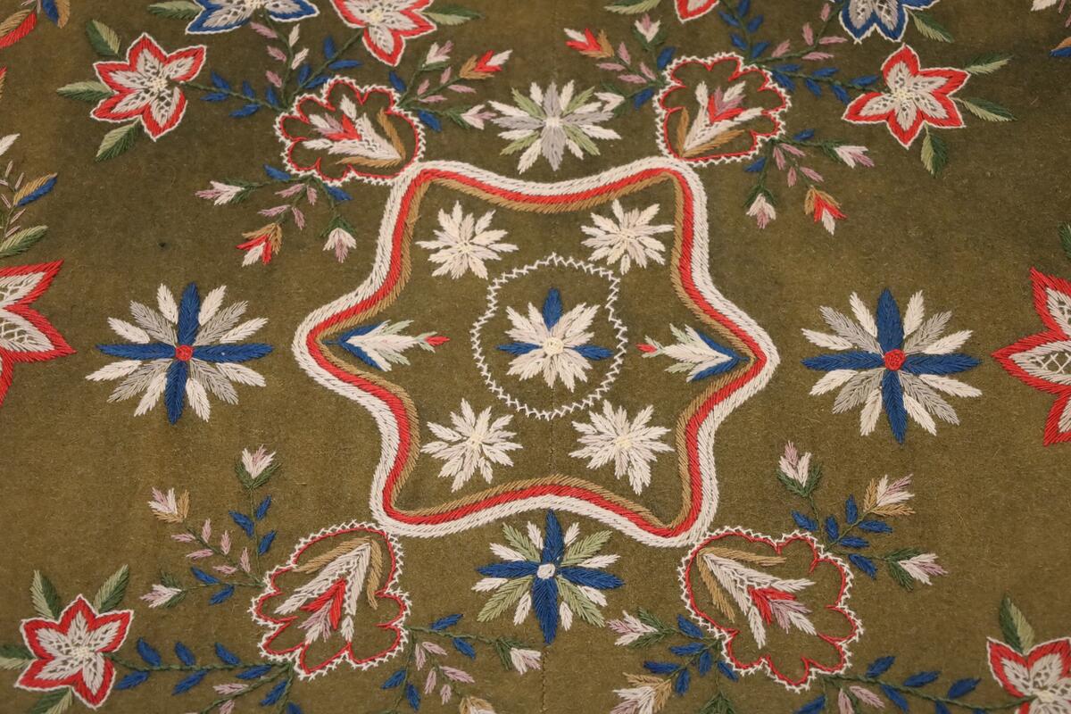 Åkle brodert med blomster, blader, bladranker og grener i ulike farger og størrelser.