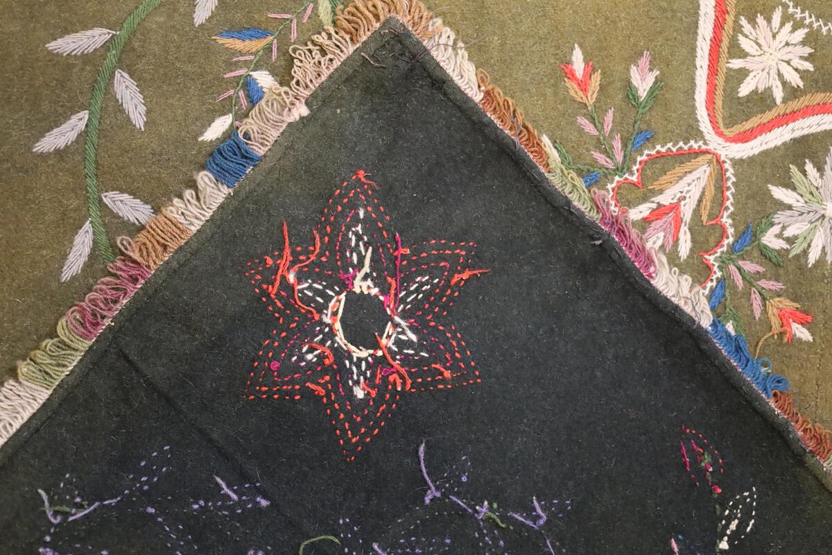 Åkle brodert med blomster, blader, bladranker og grener i ulike farger og størrelser.