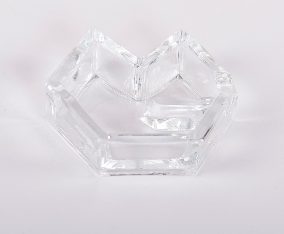 7 askebeger i klart glass formet som Moss Glassverk- logo fra Moss Glassverk. Bunn er flaskebunner, antageligvis fra 1976- 1981, ca. 6,5 cm brede og 2 cm høye uten merker/ signatur. Jmf. andre "produkter" av restglass som klosser og brevpresser.
