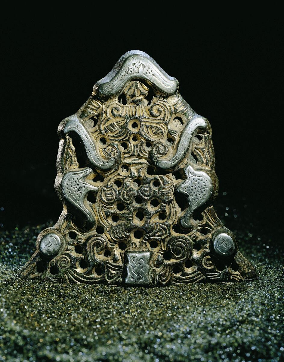 Vikingatida dräktspänne för kvinnodräkt. Spännet har dock ursprungligen varit den ena av ett par ändplattor till ett brett, sjuradigt kedjegarnityr. Kedjeplattan som ligger till grund för spännet har troligen tillverkats i början av 900-talet och senare samma århundrade gjorts om till spänne.

Gunildespännet är gjort av en dubbelsidig kedjeplatta. Framsidan är ett genombrutet arbete av förgylld brons med silverplätering. Ornamentiken består av bland annat räfflade band, flikar och bandringar och förhöjda silverpläterade fält - varav det övre i form av djurhuvuden med flygande panntofsar och därunder asymmetriska fält med punkterade ytor. Nertill på sidorna finns silverbelagda runda knoppar och i mitten en rektangulär bandflätning. Spännet avslutas överst med en silverpläterad "hatt", på vars baksida kedjeplattans hängögla är anbragt.

Basen med de sju kedjehålen sågades av när plattan gjordes om till spänne. Nålarrangemanget på baksidan består av en pålödd nålhållare och ett gångjärn som tagits från dosformiga eller djurhuvudformiga spännen.

Hittat vid hackning av konservärter i Torpåkern vid Gunilde i Sanda socken år 1927.