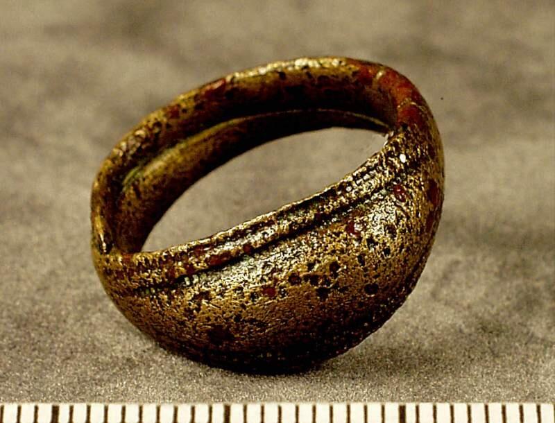 Ringens  framsida är oval och välvd ornerad med två parallella räfflade linjer längs kanterna, tenen smalnar av mot baksidan och ändarna är lagda omlott,  enligt orginalkatalogen påträffad under rovupptagning ca 1000 m sso om byggnaden
av brons, framsida i form av spetsoval, välvd platta ornerad med dubbla räfflade linjer efter kanterna. Baktill övergående i varandra passerade spetsiga ändar. Diam. 2,3 cm. Funnen vid stora velinge i buttle, under rovupptagning, cirka 1000 meter sso om byggnaden.