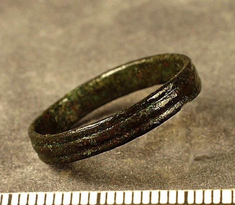 Smal sluten ring längsgående ränder på utsidan,  fynd från  undersökningen av den medeltida prästgården i bunge 1941 av gunnnar svahnström.  Fynden från undersökningen delades mellan gotlands fornsal och statens historiska museum rapport om undersökningen och fyndfördelningen finns i gotlands fornsals arkiv med koncnr 531/41och dnr 202a-c/42 kopia i ark mag
av brons, sluten, profilerad utsida. Diam. 2,2, h. 0,4 cm.