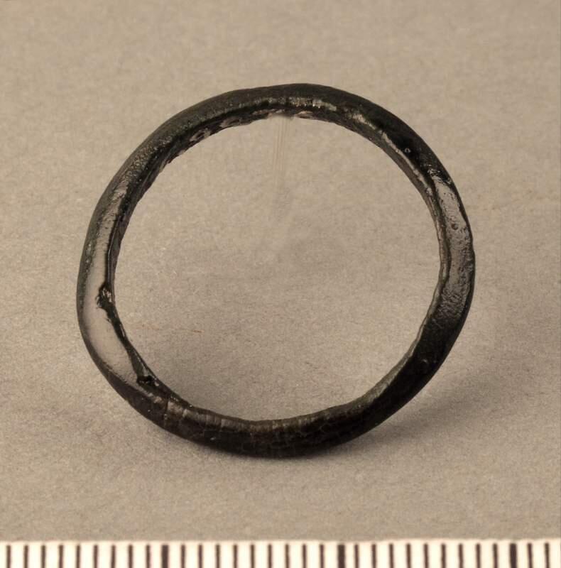 Fingerring av tunn bronsten med triangulärt tvärsnitt, sluten modell utan ornamentik, funnen som lösfynd på gravfältet vid västerbjärs
av brons, ojämt rundad, triangulärt snitt. Diam. 14,5 cm. Funnen på gravfältet, västerbjärs i gothem.