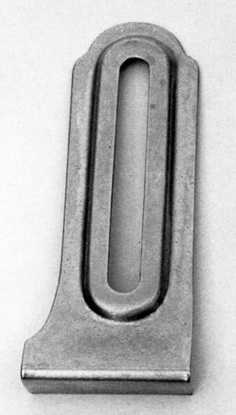 a) Symaskin av märket Husqvarna, modell V.S.4. Handdriven. Svartmålad på träplatta. Nersänkt låda med tillbehör. b) Huv av ekfaner. Handtag på toppen. c) Skyttel av stål. Rund, spetsig i ena änden, rak i den andra. Innehåller en spole med vit tråd. d) Fem spolar av stål. Rund stav med plattor i ändarna. Olika trådrester. e) Ledpressarfot (monterad på maskinen). f) Fållvikare 2 mm. g) Fållvikare 6 mm. h) Gansapparat. i) Rynkfot .j) Linjal. Längd 5,3 cm. k) Fem symaskinsnålar i olika grovlekar. Cellofanförpackning. l) Skruvnyckel. Typ lång platt nål, bakre delen försedd med runt hål. m) Skruvmejsel av stål. Fäste av svart bakelit. n) Borste av dubbelvriden ståltråd med en borste i ena änden. o) Skruvmejsel av stål. Fäste av svart bakelit. p) Provlapp av bomullsflanell. För kontroll av stygnställning. q) Provlapp av bomyllskypert. Till kontroll av stygnställning. r) Bruksanvisning. Tryckt broschyr på 30 sidor.