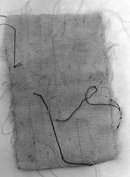 a) Symaskin av märket Husqvarna, modell V.S.4. Handdriven. Svartmålad på träplatta. Nersänkt låda med tillbehör. b) Huv av ekfaner. Handtag på toppen. c) Skyttel av stål. Rund, spetsig i ena änden, rak i den andra. Innehåller en spole med vit tråd. d) Fem spolar av stål. Rund stav med plattor i ändarna. Olika trådrester. e) Ledpressarfot (monterad på maskinen). f) Fållvikare 2 mm. g) Fållvikare 6 mm. h) Gansapparat. i) Rynkfot .j) Linjal. Längd 5,3 cm. k) Fem symaskinsnålar i olika grovlekar. Cellofanförpackning. l) Skruvnyckel. Typ lång platt nål, bakre delen försedd med runt hål. m) Skruvmejsel av stål. Fäste av svart bakelit. n) Borste av dubbelvriden ståltråd med en borste i ena änden. o) Skruvmejsel av stål. Fäste av svart bakelit. p) Provlapp av bomullsflanell. För kontroll av stygnställning. q) Provlapp av bomyllskypert. Till kontroll av stygnställning. r) Bruksanvisning. Tryckt broschyr på 30 sidor.