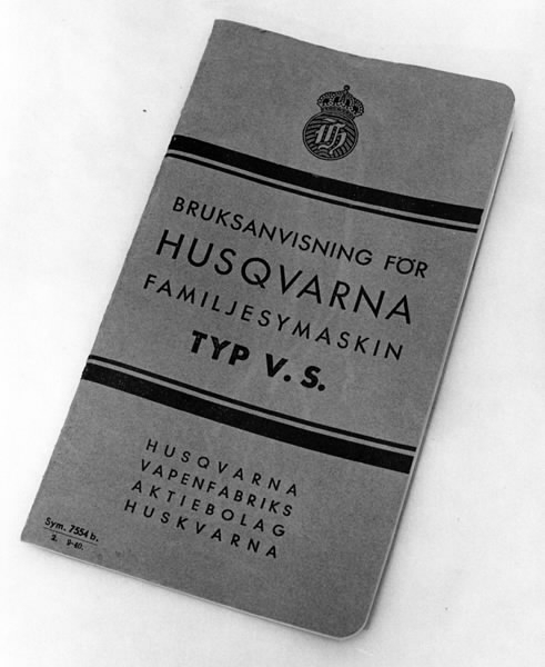 a) Symaskin av märket Husqvarna, modell V.S.4. Handdriven. Svartmålad på träplatta. Nersänkt låda med tillbehör. b) Huv av ekfaner. Handtag på toppen. c) Skyttel av stål. Rund, spetsig i ena änden, rak i den andra. Innehåller en spole med vit tråd. d) Fem spolar av stål. Rund stav med plattor i ändarna. Olika trådrester. e) Ledpressarfot (monterad på maskinen). f) Fållvikare 2 mm. g) Fållvikare 6 mm. h) Gansapparat. i) Rynkfot .j) Linjal. Längd 5,3 cm. k) Fem symaskinsnålar i olika grovlekar. Cellofanförpackning. l) Skruvnyckel. Typ lång platt nål, bakre delen försedd med runt hål. m) Skruvmejsel av stål. Fäste av svart bakelit. n) Borste av dubbelvriden ståltråd med en borste i ena änden. o) Skruvmejsel av stål. Fäste av svart bakelit. p) Provlapp av bomullsflanell. För kontroll av stygnställning. q) Provlapp av bomyllskypert. Till kontroll av stygnställning. r) Bruksanvisning. Tryckt broschyr på 30 sidor.