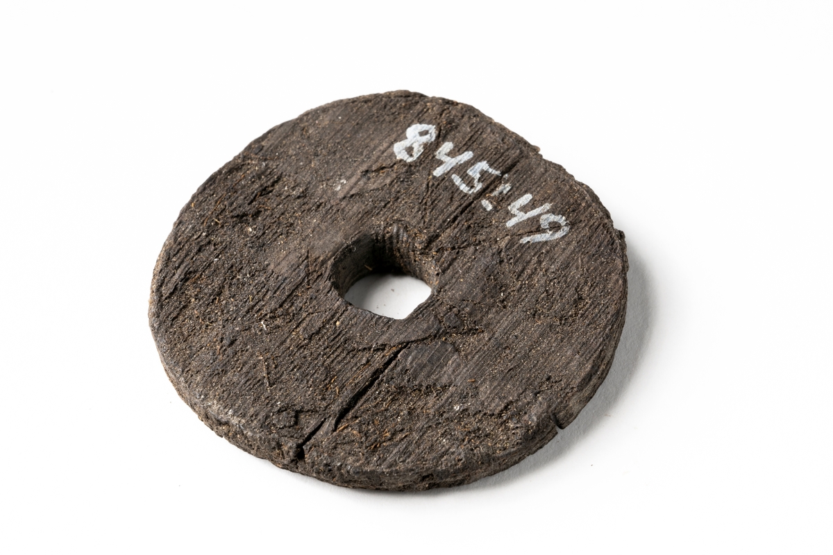 Troligtvis ett flöte. Föremålet beskrivs i den ursprungliga föremålskatalogen som "runt föremål av trä med isittande pinne"... "Diam. 5 cm. Pinnens längd 3,5 cm". Idag saknas pinnen.