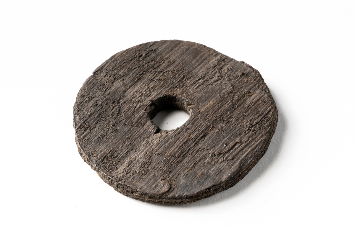 Troligtvis ett flöte. Föremålet beskrivs i den ursprungliga föremålskatalogen som "runt föremål av trä med isittande pinne"... "Diam. 5 cm. Pinnens längd 3,5 cm". Idag saknas pinnen.