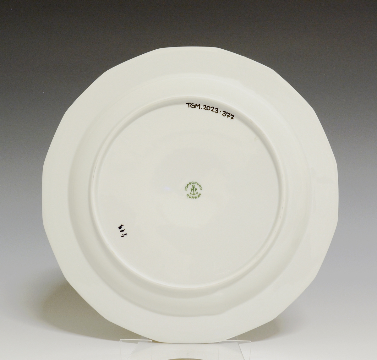 Mangekantet tallerken av porselen med hvit glasur. 
Modell: Octavia, tegnet av Grete Rønning i 1977.
