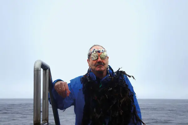 En mann står i en badetrapp med skjell over øynene