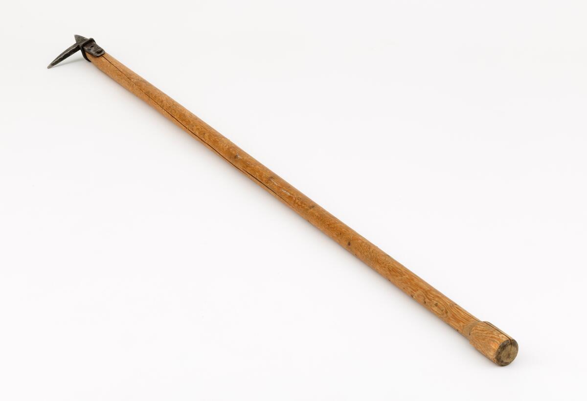 Fløterhake av «østerdalstypen». Haken har et kraftig skaft av ubehandlet gran. Bakerst har skaftet en fortykning. Haken er festet til skaftet med en jernring og en hjemmesmidd spiker. Stempelet «PW» viser at redskapet er produsert av smeden Per Wolla, Heradsbygd, Elverum.