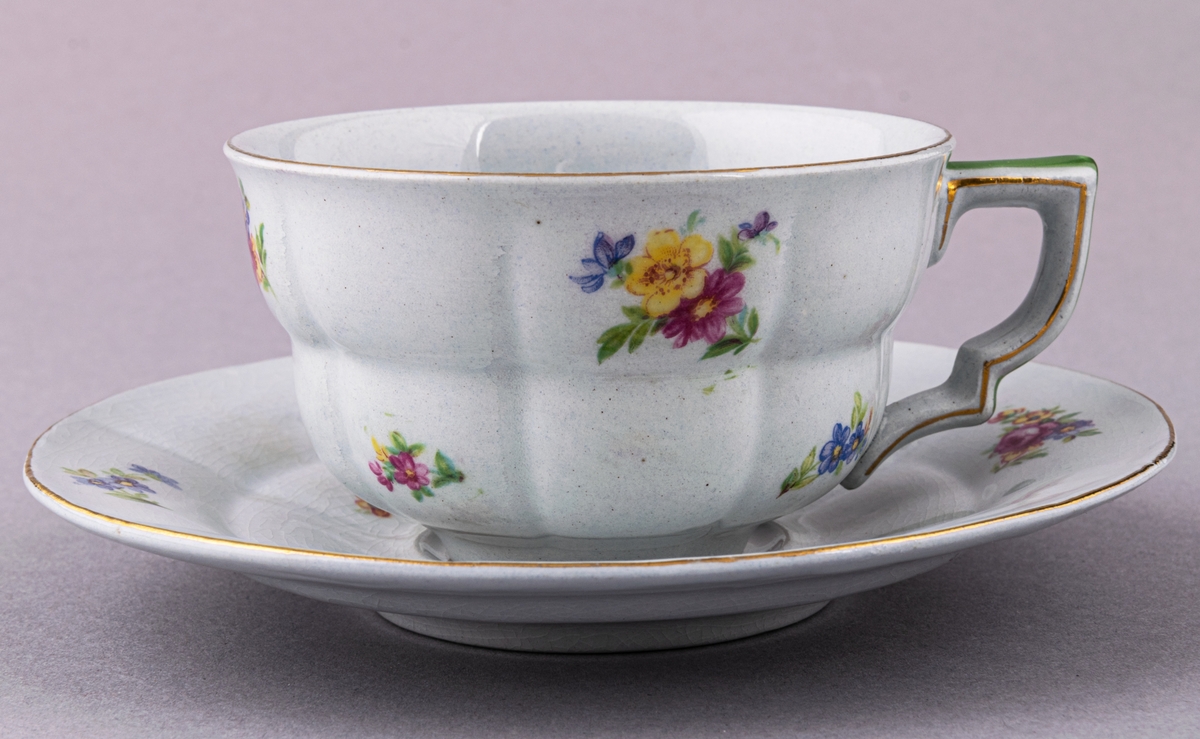 Kaffekopp med fat, i flintgods. Modelll AB, dekor Rosaslie. Ljusblå glasyr med blommönster. Skapad av Eugen Trost för Gefle Porslinsfabrik 1939.