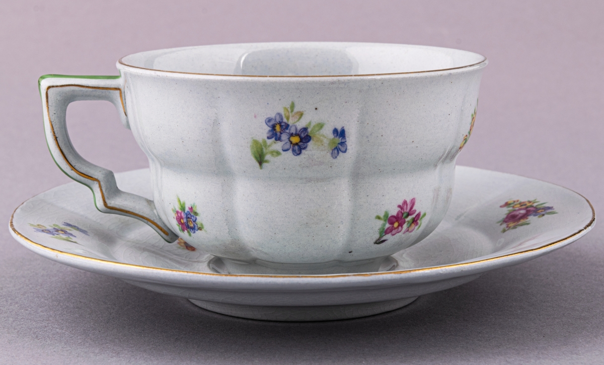 Kaffekopp med fat, i flintgods. Modelll AB, dekor Rosaslie. Ljusblå glasyr med blommönster. Skapad av Eugen Trost för Gefle Porslinsfabrik 1939.